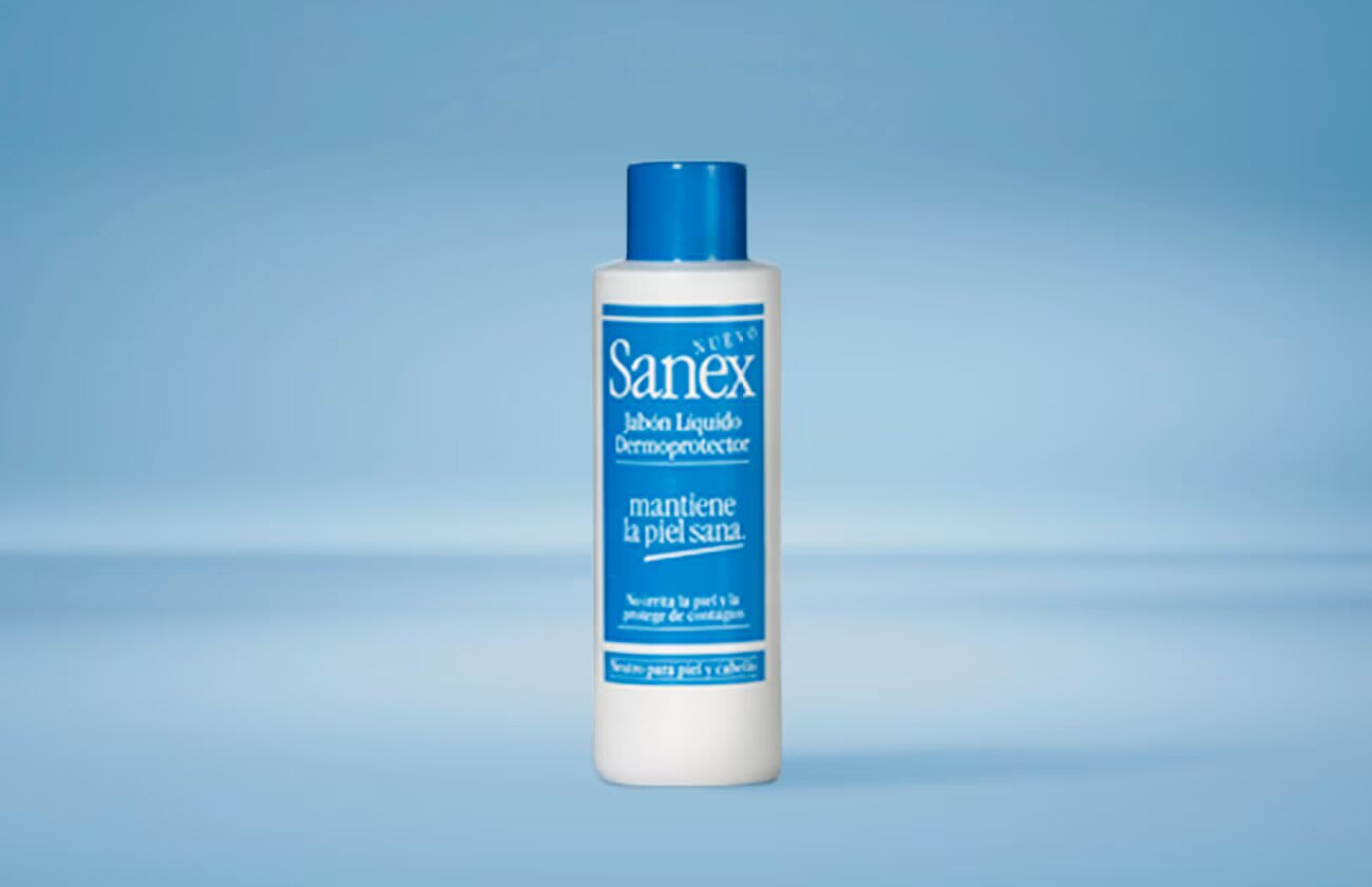 Een fles Sanex vloeibare dermoprotector zeep, met een blauwe dop, tegen een lichtblauwe achtergrond.